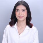 Patricia Lazatin Portrait | ACCUR Recruiting Services Smiling woman with dark wavy hair, wearing a white button-up shirt and a delicate necklace, against a light gray background.